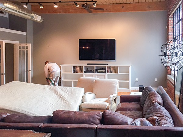 Furniture covered and protected while a painter prepares a living room
