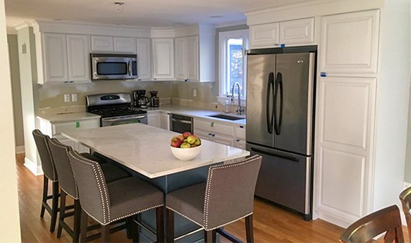 A finished kitchen with freshly painted white cabinets and island