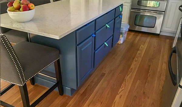 A kitchen island painted deep blue with a marble top