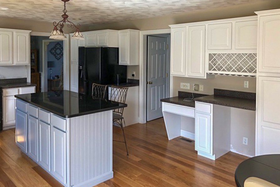 A finished kitchen with white painted cabinets and a large island