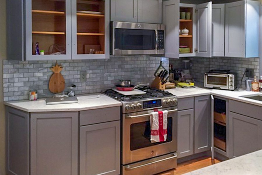 A kitchen with freshly painted gray cabinets and new hardware